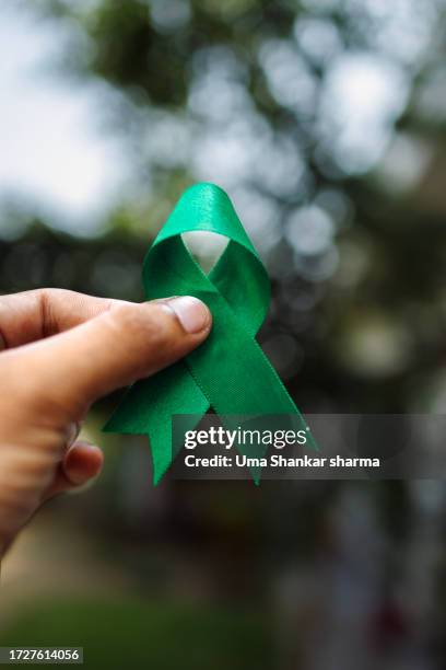 hand holding green ribbon, mental health awareness symbol. - lymphoma stock pictures, royalty-free photos & images