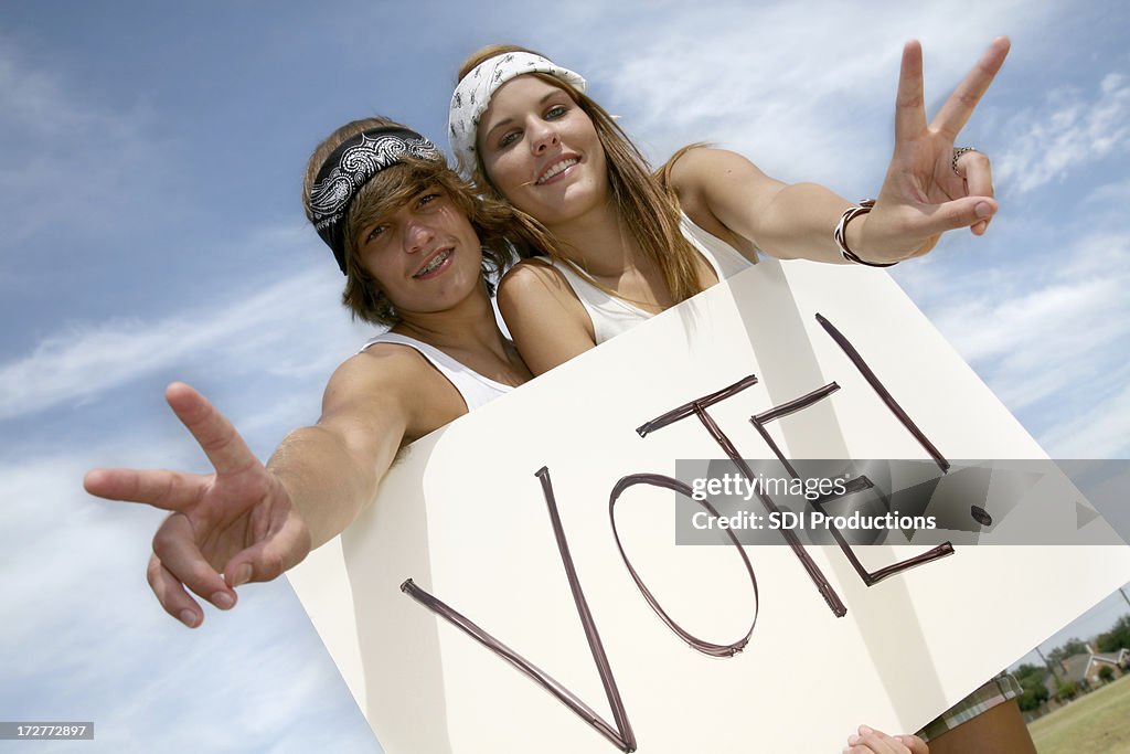 Young Hippie Couple Holding Vote Sign Making Peace Hand Gesture