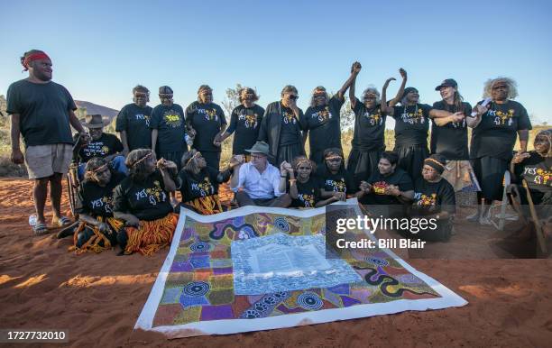 Australian prime minister Anthony Albanese sits with Indigenous men and women as they pose for a photo with a copy of the Uluru Statement from the...
