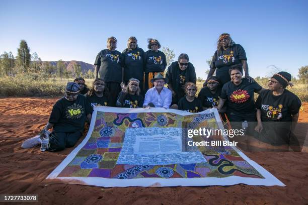 Australian prime minister Anthony Albanese sits with Indigenous women as they pose for a photo with a copy of the Uluru Statement from the Heart in...