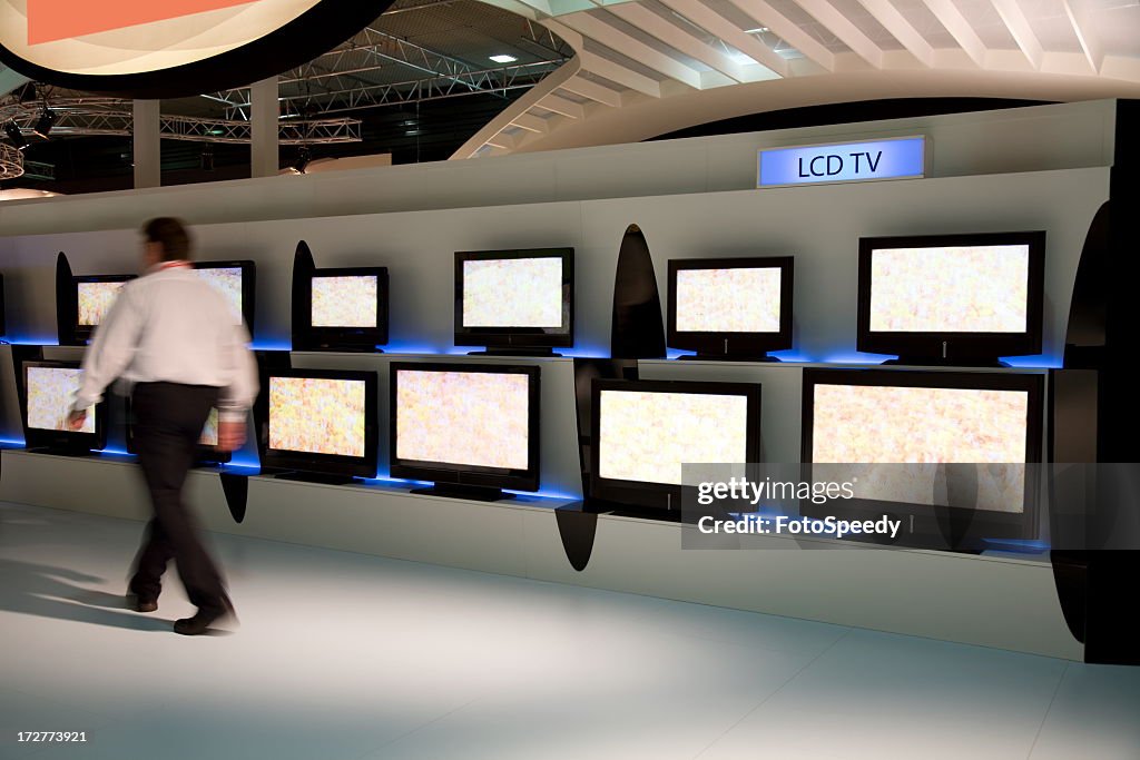 Man walking by various displays of LCD TV