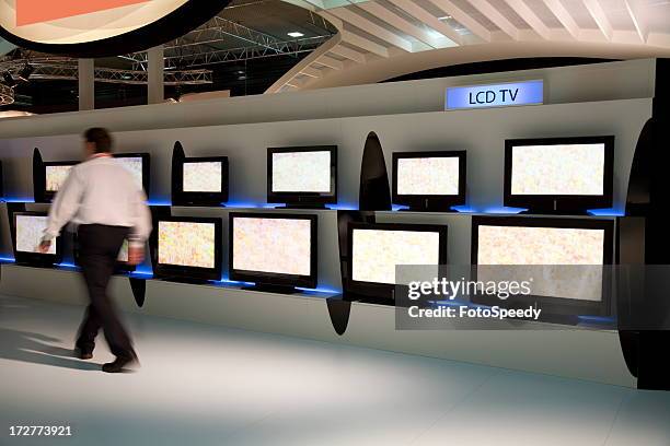 man walking by various displays of lcd tv - tv store stock pictures, royalty-free photos & images