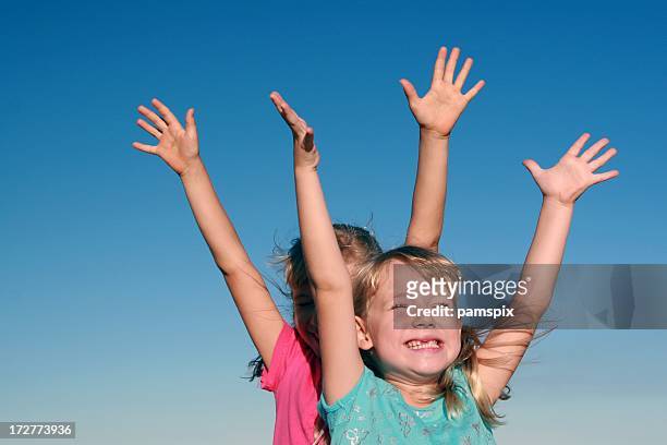 girls with arms raised on blue sky background - child reaching stock pictures, royalty-free photos & images