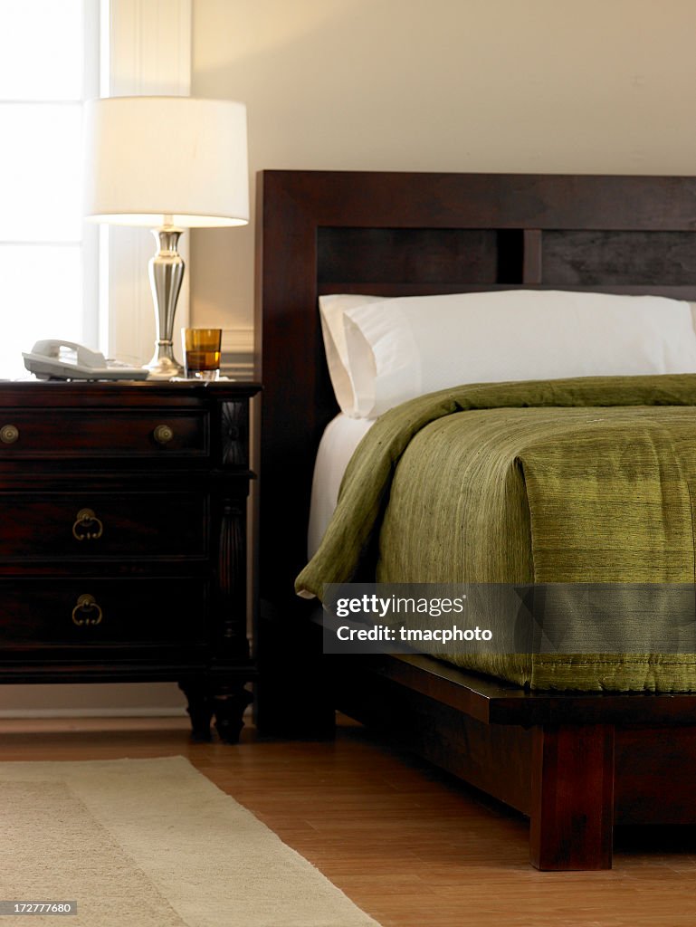 Hotel room with dark wood furniture and green bedding