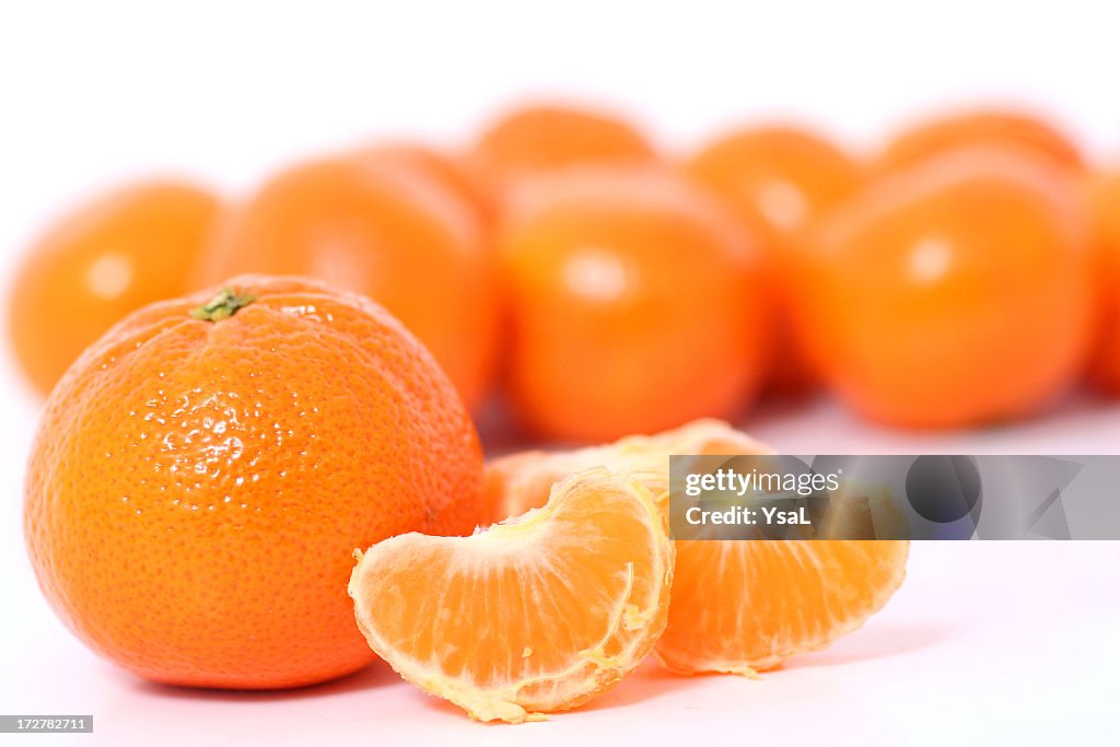 Tangerines and clementine wholes and slices on white