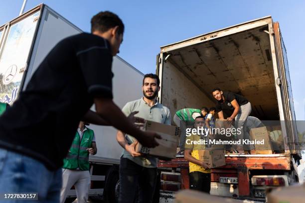 Volunteers load food and supplies onto trucks in an aid convoy for Gaza on October 16, 2023 in North Sinai, Egypt. The aid convoy, organized by a...