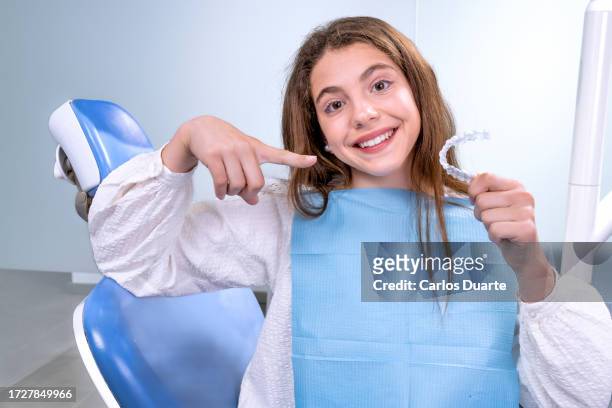 teenage girl goes to the dentist to receive modern orthodontic treatment to correct the alignment of her teeth - invisalign stockfoto's en -beelden