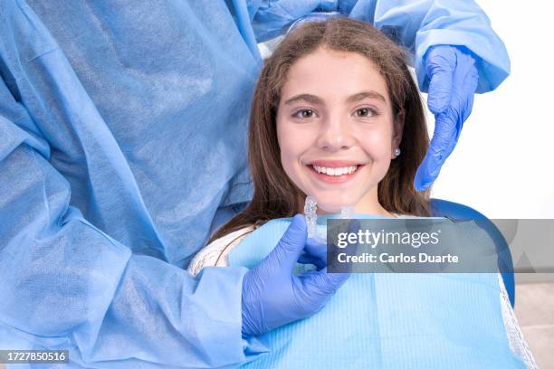 teenage girl goes to the dentist to receive modern orthodontic treatment to correct the alignment of her teeth - aparelho dentário imagens e fotografias de stock