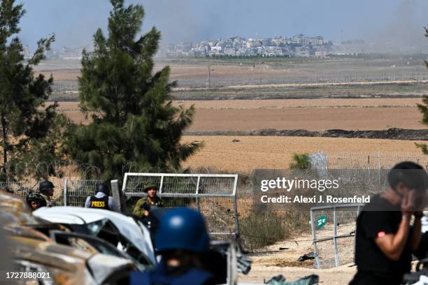 Member of the press wipes his eyes in front of the spot Hamas militants broke through the kibbutz Kfar Aza's fence days earlier, with a view of Gaza...