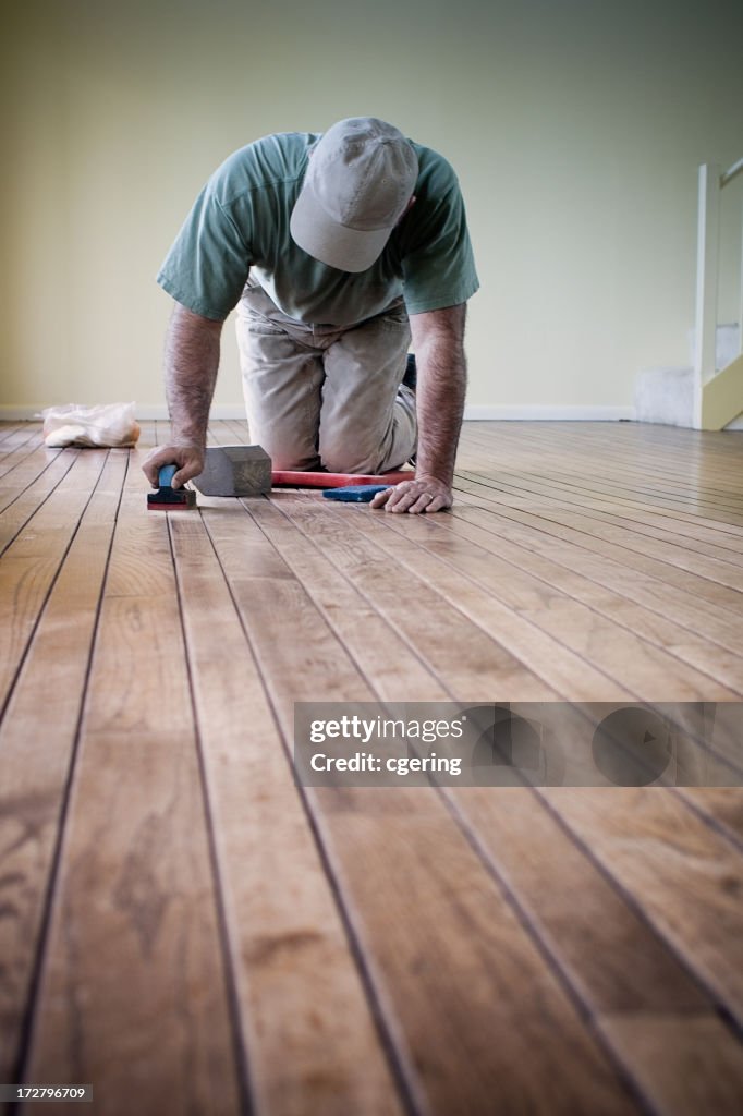 Worker putting finishing details on hardwood flooring