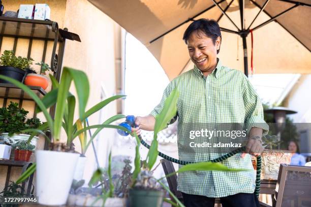 mature filipino man working in the garden - garden hose stock pictures, royalty-free photos & images