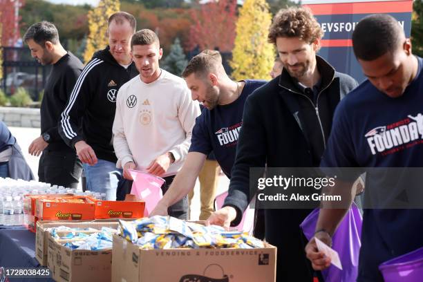 Arne Friedrich and Robin Gosens of the German national team and Raekwon McMillan of the New England Patriots help packing goods for the local...