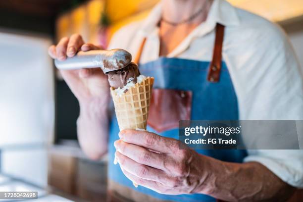 primer plano de un vendedor de helados preparando helados en una heladería - barquilla de helado fotografías e imágenes de stock