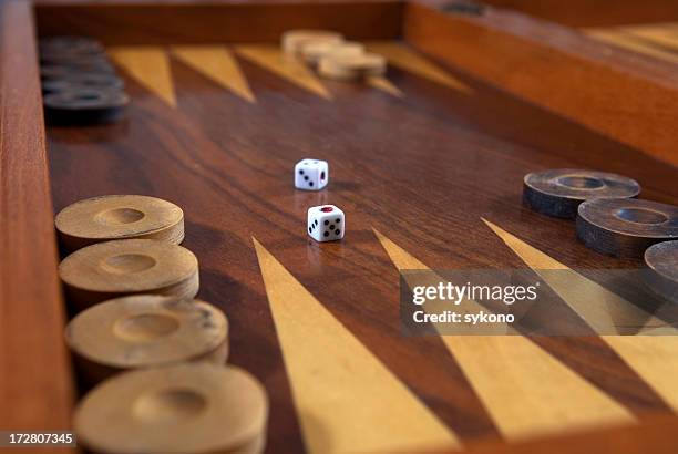 backgammon board in polished wood with die centrally placed - backgammon stock pictures, royalty-free photos & images