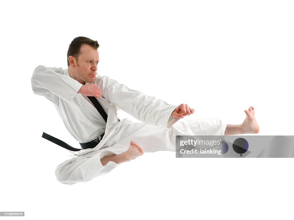 Portrait of a black belt man doing a high kick on white