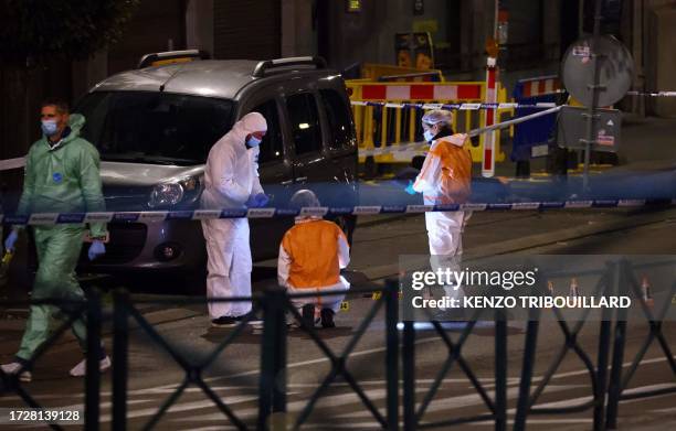 Belgian police officers from the forensic service search for evidence in a street after two people were killed during a shooting in Brussels on...