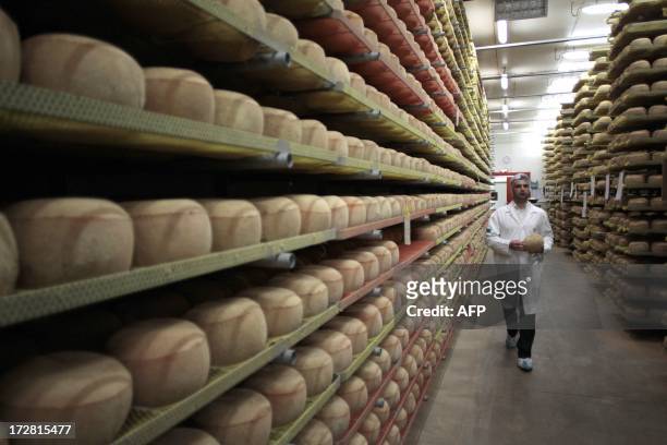 Cheesemonger walks along mimolette cheese in a production site of the French Isigny Ste Mere company on July 4, 2013 in Isigny-sur-Mere, northwestern...
