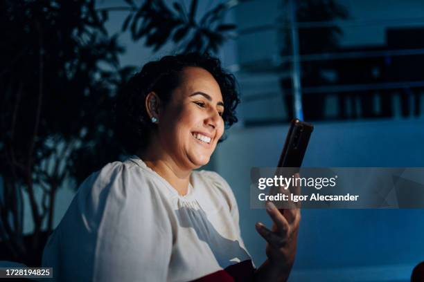 woman watching videos on her smartphone at night - game console stockfoto's en -beelden