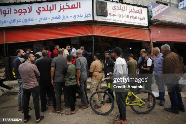 Palestinians line up in front of a bakery to buy bread after Israel restricts the area of basic services such as water, electricity, and food in Deir...