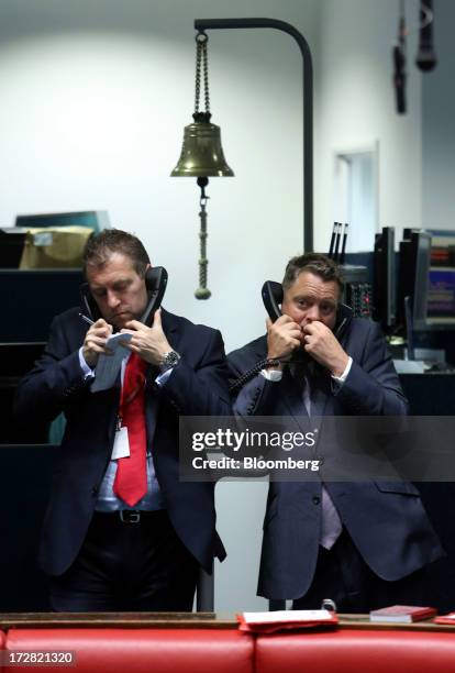 Bell hangs beyond traders as they use telephones while working outside the open outcry pit on the trading floor of the London Metal Exchange in...