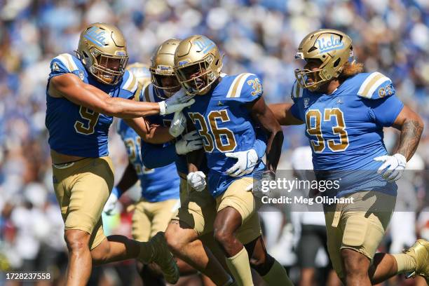 Alex Johnson of the UCLA Bruins celebrates with Choe Bryant-Strother and Jay Toia after intercepting the ball against the Washington State Cougars in...