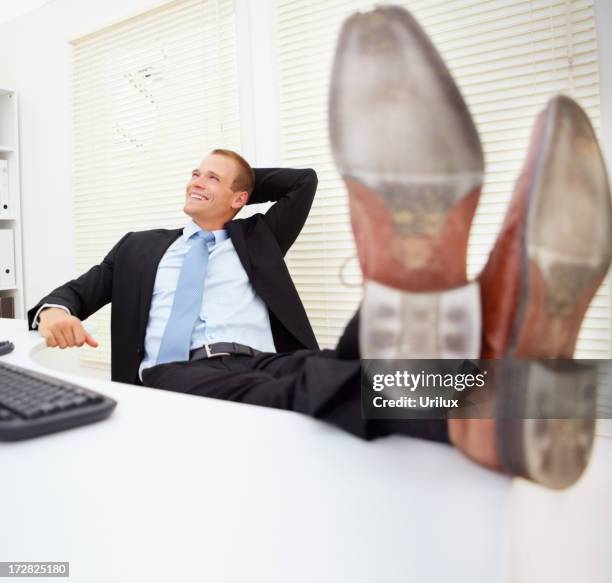 handsome business man sitting in office with legs over table - legs on the table stock pictures, royalty-free photos & images