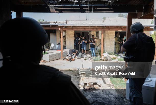 Members of the media take cover under destroyed homes after hearing loud rocket and gun fire while visiting Kfar Aza where Hamas militants attacked...