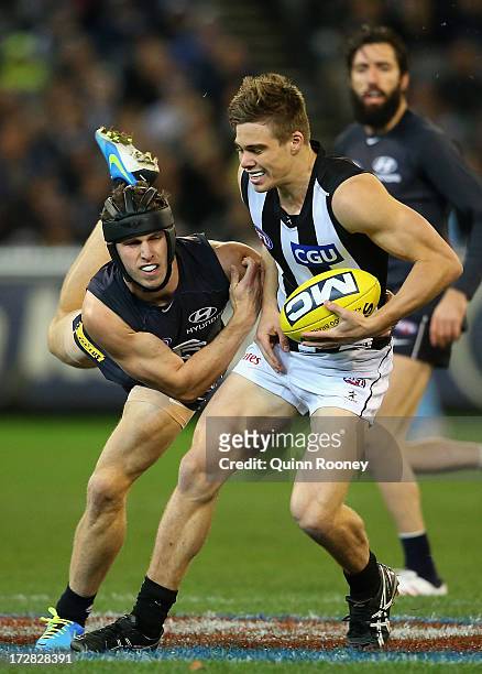 Josh Thomas of the Magpies is tackled by Marc Murphy of the Blues during the round 15 AFL match between the Carlton Blues and the Collingwood Magpies...