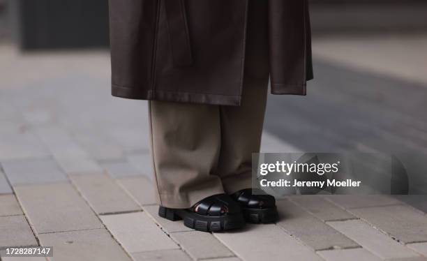 Maria Barteczko is seen wearing a brown oversized long leather coat from Low Classic, light brown wide leg pants from Zara and black fisherman...