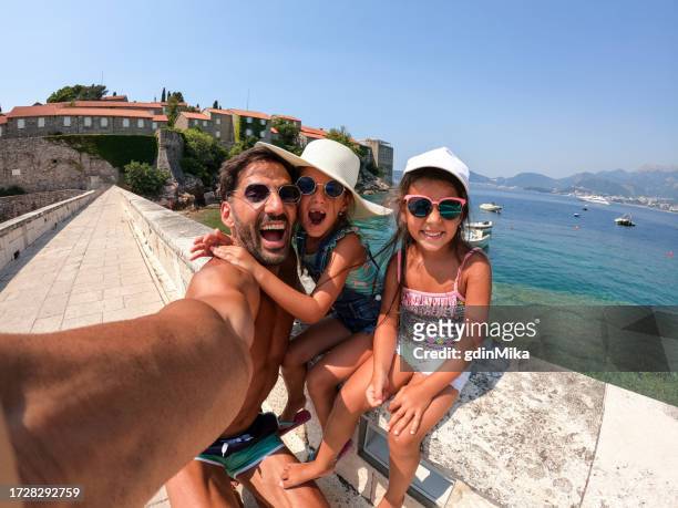 posing father with two silly daughters on beach in montenegro - sveti stefan stock pictures, royalty-free photos & images