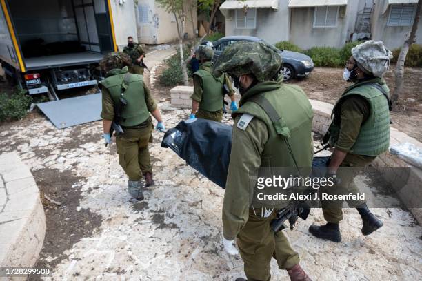 Soldiers remove the body of civilians who were killed days earlier in an attack by Hamas militants on this kibbutz near the border with Gaza, on...