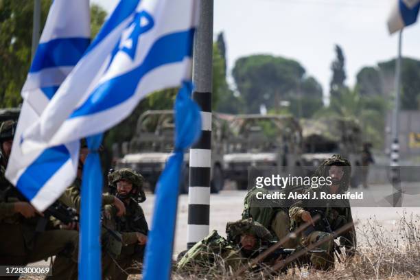 Soldiers guard near a waving Israeli flag outside Kibbutz Kfar Aza where dozens of civilians were killed days earlier in an attack by Hamas militants...