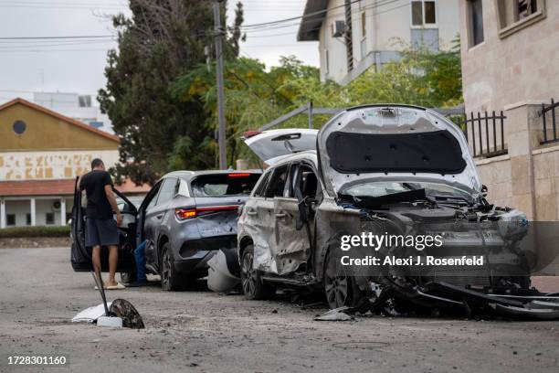 People look at their cars after they were hit by a rocket a day earlier on October 10, 2023 in Ashkelon, Israel. Israel has sealed off Gaza and...