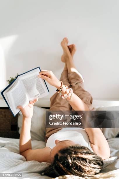 portrait of a woman with book lying on the bed - krampfader stock-fotos und bilder