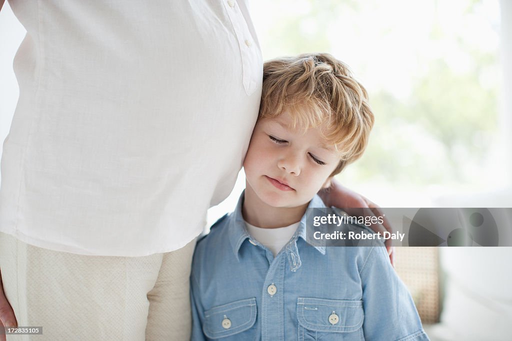 Boy leaning against pregnant mothers stomach