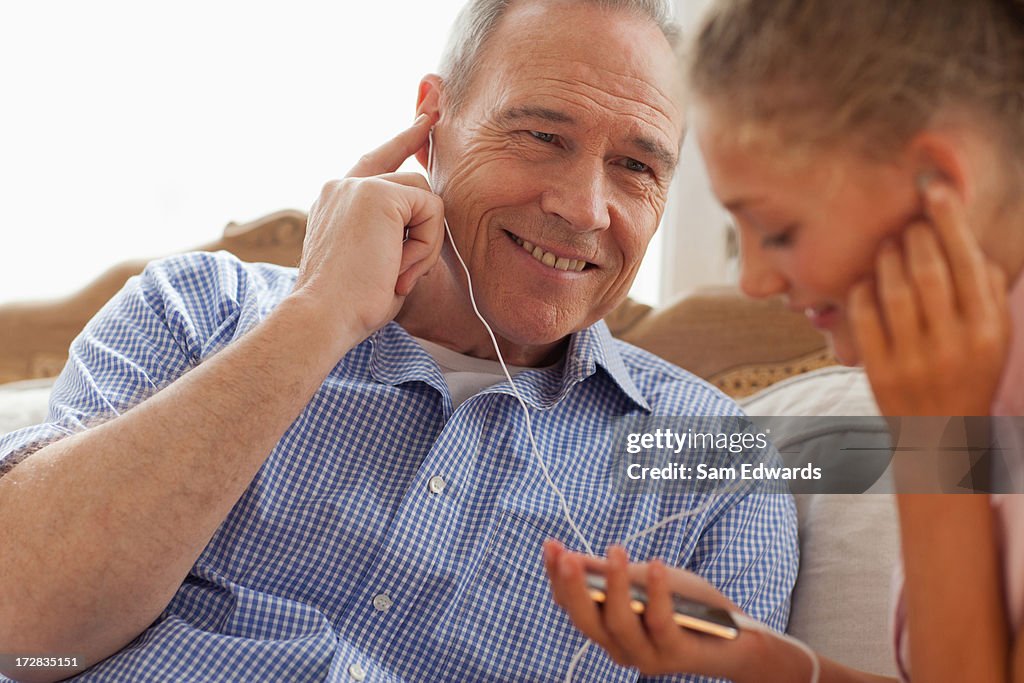 Abuelo y granddaughter compartir auriculares y escuchar música