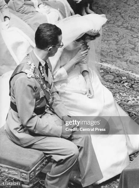 King Baudouin of Belgium shows concern for his bride, Queen Fabiola of Belgium, as she uses smelling salts during their wedding ceremony at the...