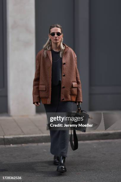 Kathrin Bommann is seen wearing sunglasses with silver frame from Chanel, golden chunky hoop earrings, several golden necklaces, a brown leather...