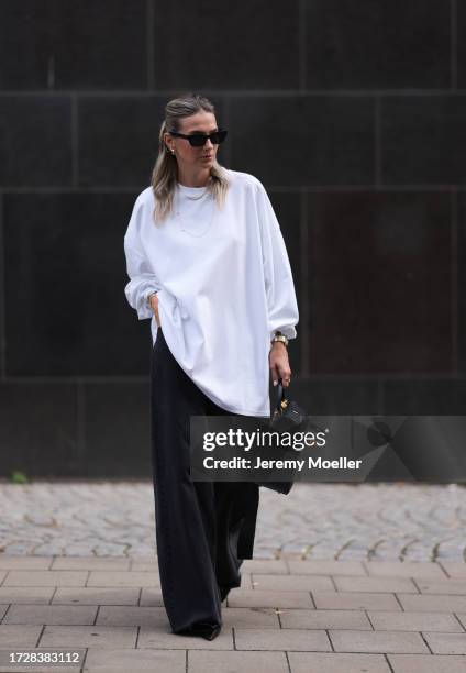 Kathrin Bommann is seen wearing black sunglasses from Céline, golden chunky hoop earrings, several ear studs, several golden necklaces, a white long...