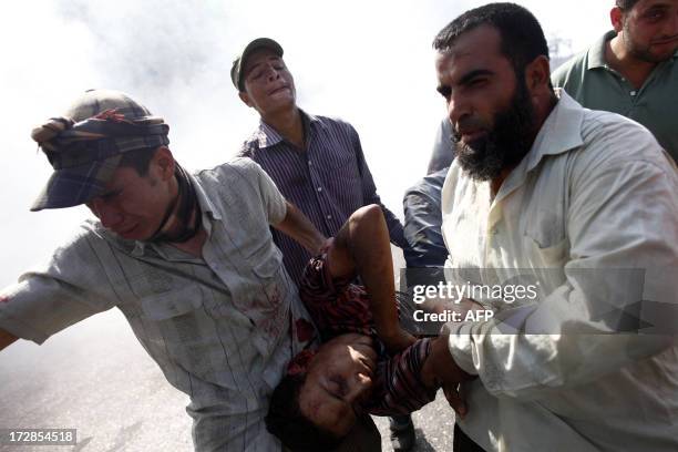 Supporters of ousted Egyptian president Mohamed Morsi carry a man who was shot during a gun battle outside the Cairo headquarters of the Republican...