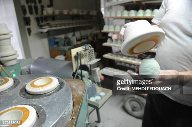 An employee of porcelaine manufacturing society JL Coquet is at work at a plant in Saint-Leonard-de-Noblat near Limoges, on July 5, 2013. AFP PHOTO...