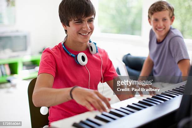 teenage boy watching friend play electronic piano keyboard - keyboard white stockfoto's en -beelden