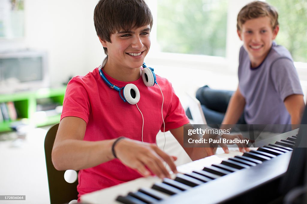 Teenage boy watching friend play electronic piano keyboard