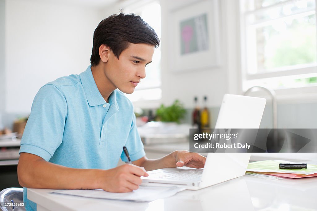 Teenage boy using laptop and doing homework