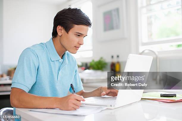 teenage boy using laptop and doing homework - homeschool 個照片及圖片檔