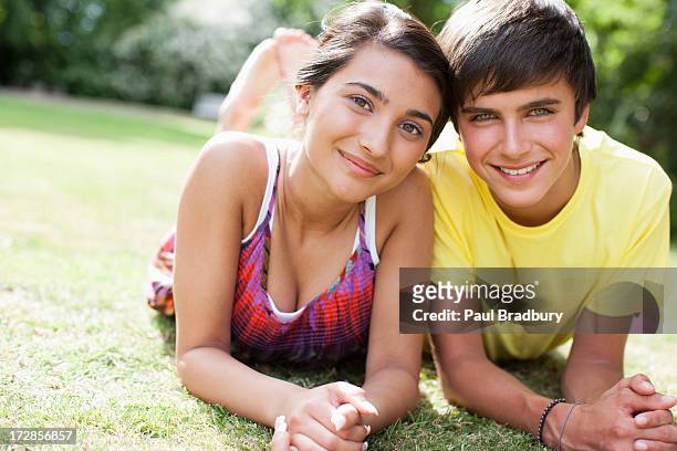 sorridente casal adolescente pôr na grama juntos - casal adolescente imagens e fotografias de stock