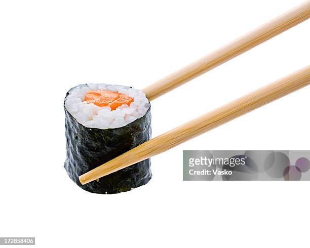 a sushi roll with salmon being held by wooden chopsticks - chopsticks stock pictures, royalty-free photos & images