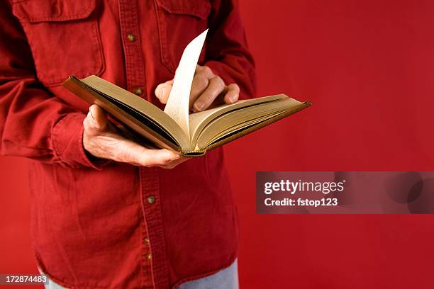 man reading book. red background. holding open. - open bible stock pictures, royalty-free photos & images