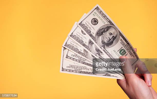 a hand holding five $100 bills - holding stock pictures, royalty-free photos & images