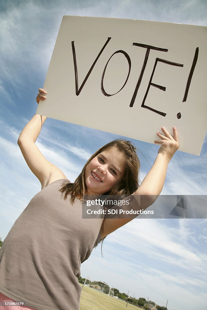 Giovane ragazza tenendo votazione firmare In aria esterno